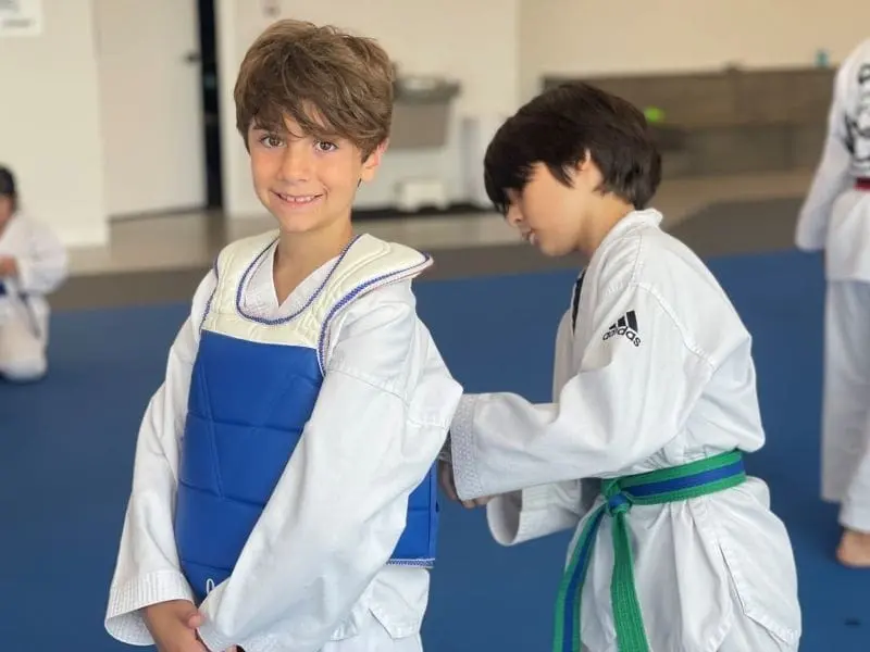 Youth martial arts students putting on sparring gear before class