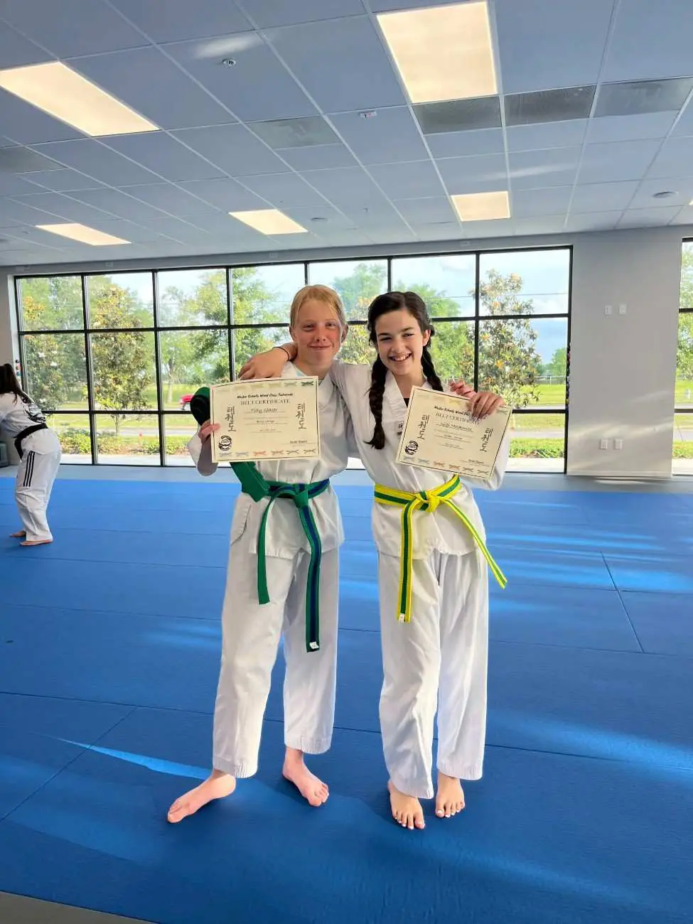 Martial arts belt promotion ceremony with students holding certificates