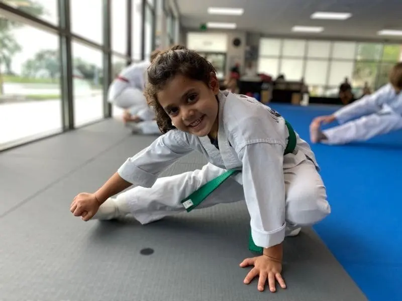 young girl stretching before the start of martial arts lessons