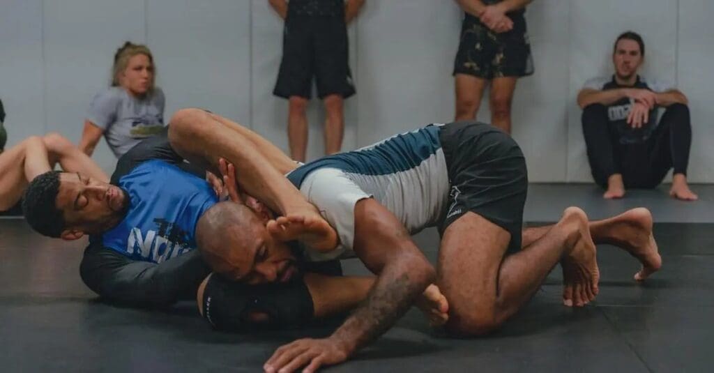 Two adult martial artists practicing ground grappling techniques on mats during adults martial arts for beginners training.
