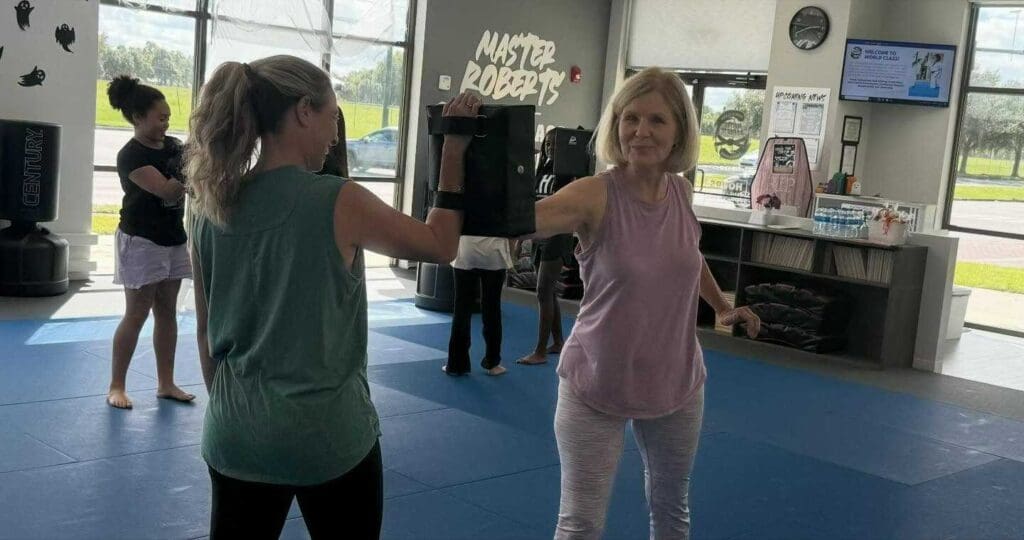 Adult student practicing a controlled punch against a pad during a self-defense training session, learning self defense principles for beginners.